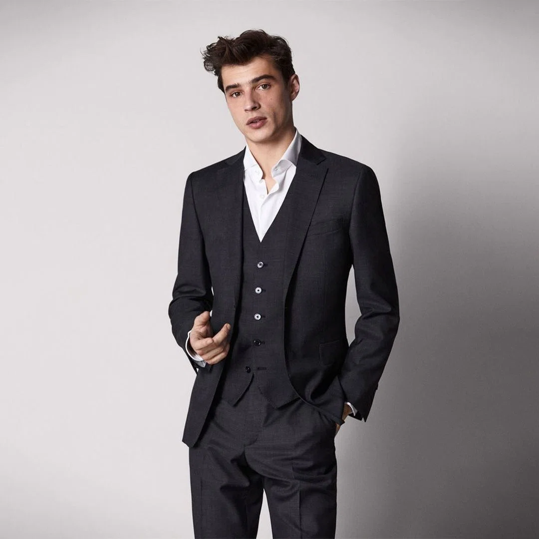 Detailed shot of a sleek black tuxedo jacket with an embroidered company logo on the chest, symbolizing high quality branding.